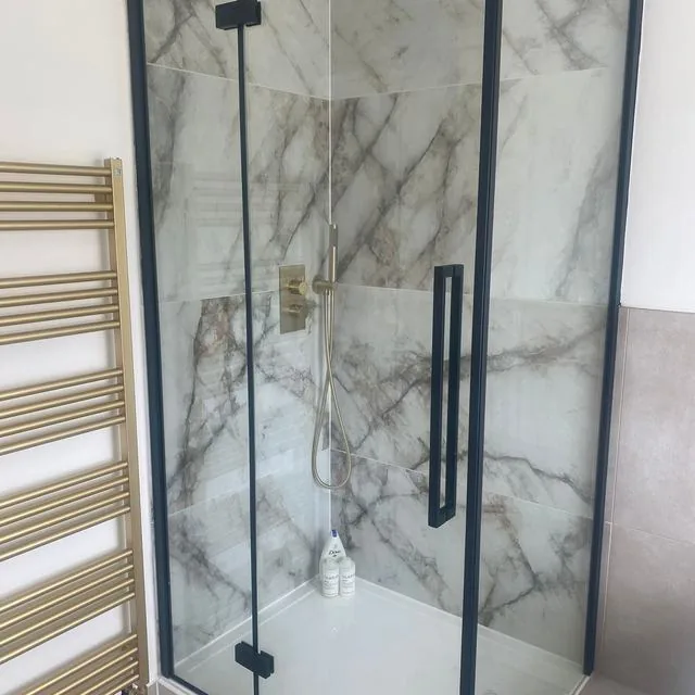 A marble tiled shower enclosure with brushed brass fittings