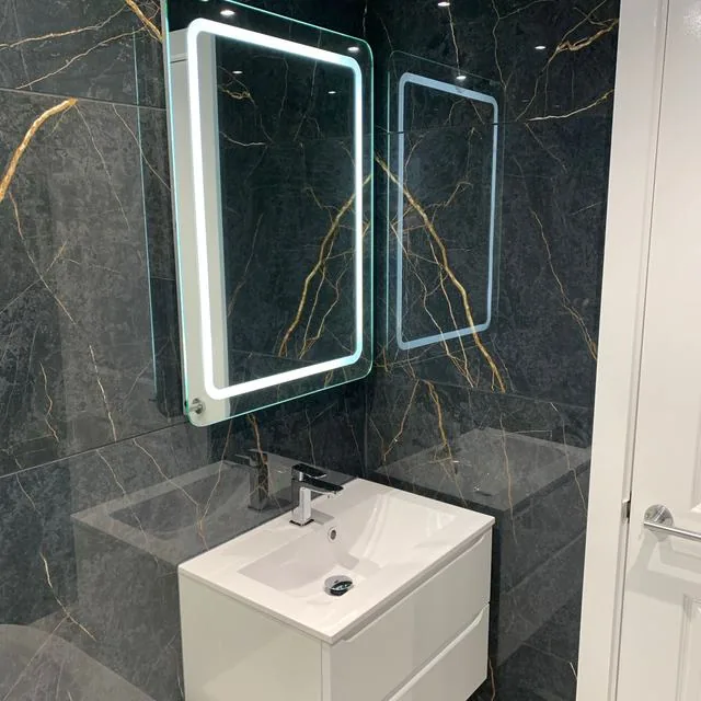A bathroom refit with a bath, shower screen and tiled walls