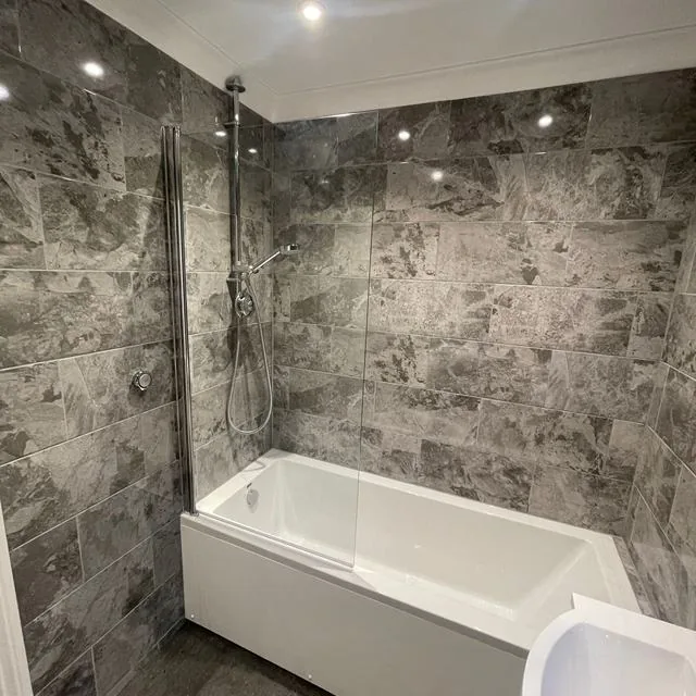 A bathroom with a bath, wall hung toilet and vanity unit