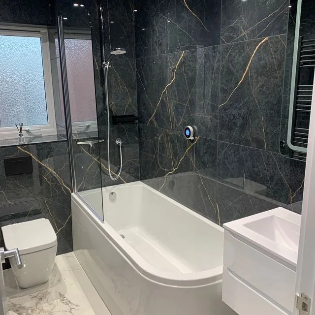 A bathroom walled in dark marble with a bath and shower over it