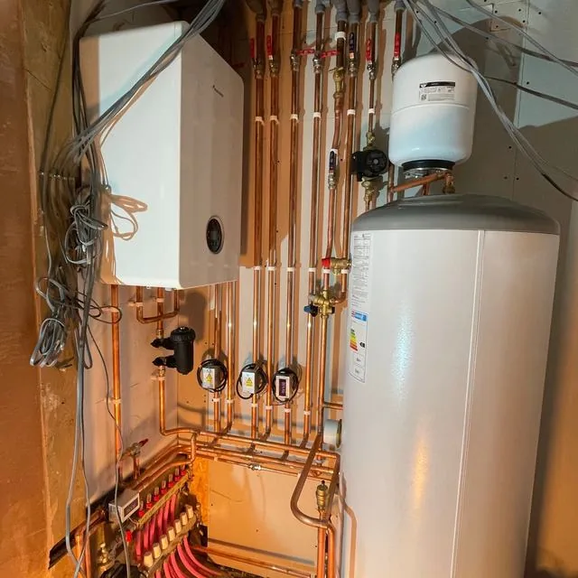 A boiler, hot water cylinder and copper pipework in an airing cupboard