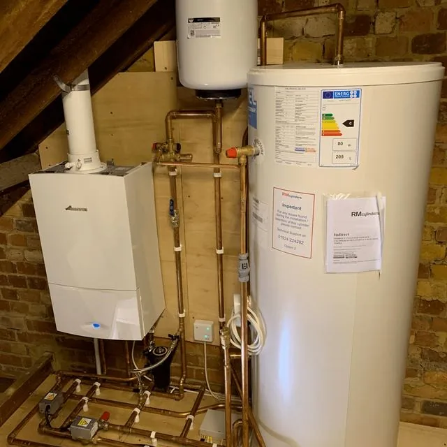 A boiler and unvented hot water cylinder installed in a loft with copper pipework