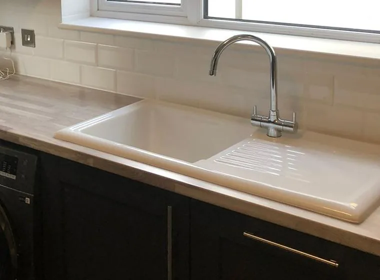 A kitchen sink and mixer tap plumbed in beside a washing machine