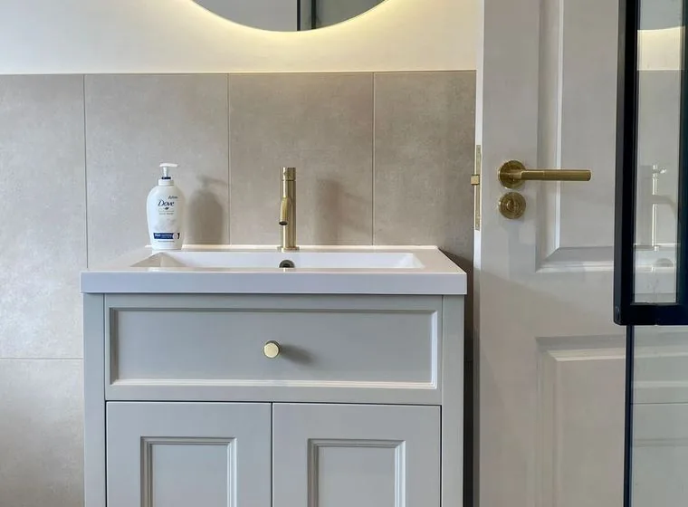 A brushed brass basin mixer tap on a vanity unit